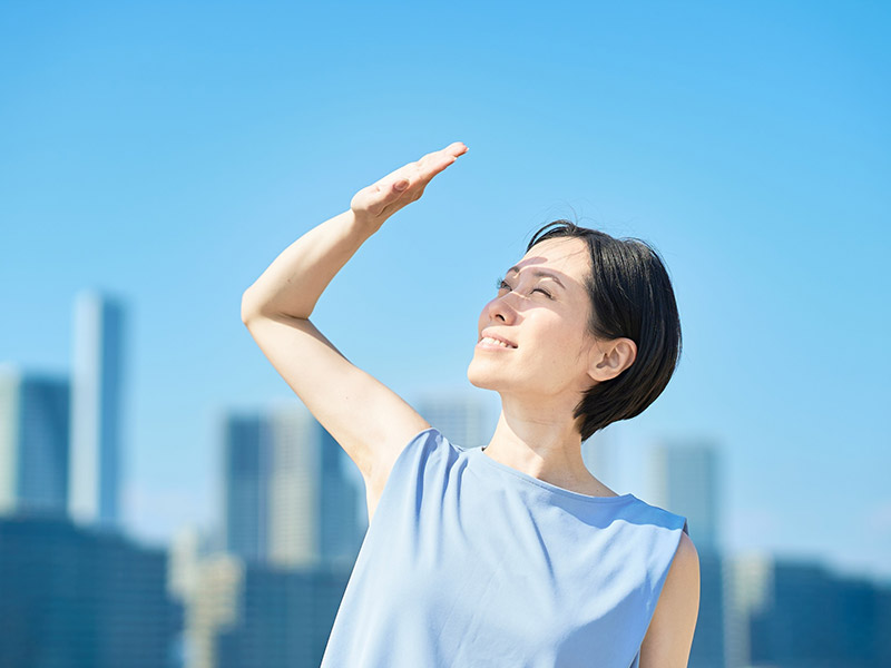 A woman squinting in bright sunlight, illustrating the need for photophobia sunglasses to manage glare and eye sensitivity.