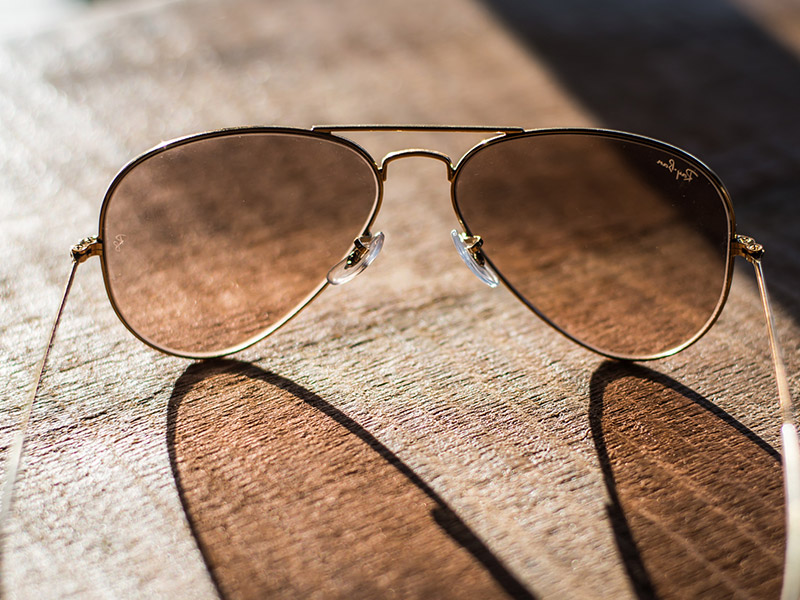 A close-up of aviator sunglasses with brown tinted lenses, an effective and soothing lens color for managing photophobia and light sensitivity.